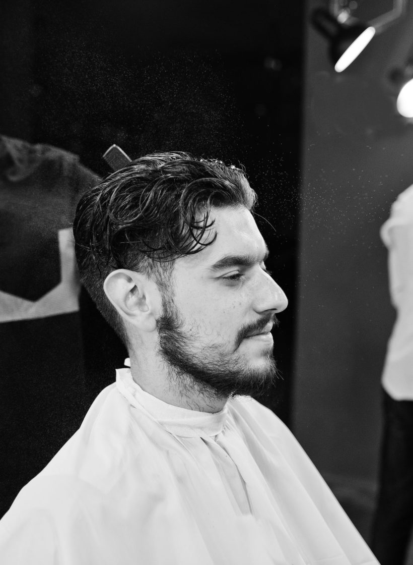 Handsome bearded man at the barbershop, barber at work.